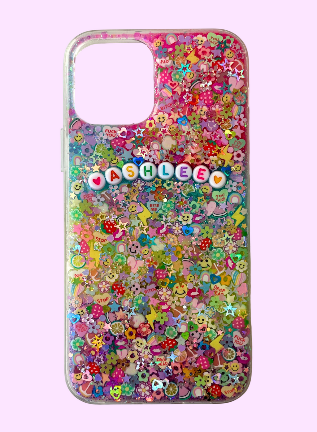 Colorful resin-style phone case filled with multicolored glitter, flowers, stars, smiley faces, fruit and novelty polymer clay slices, featuring white round letter beads spelling ‘ASHLEE’ with heart accents