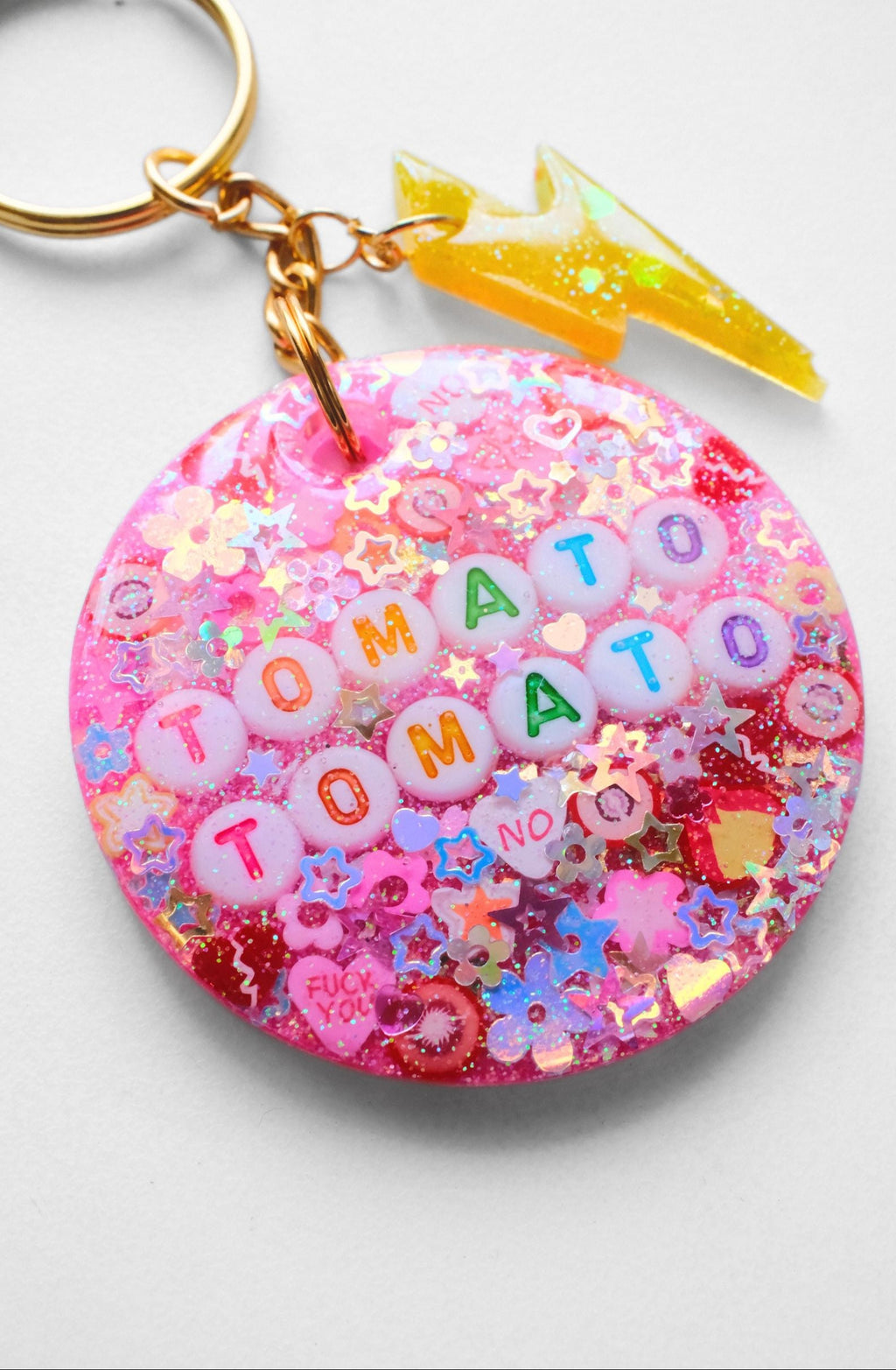 Colorful keychain with 'Tomato Tomato' text and decorative elements on a white background