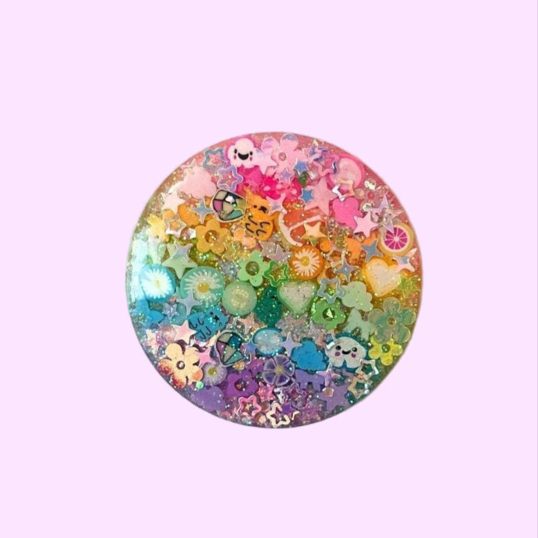 Colorful decorative button with floral and cartoon designs on a white background